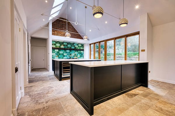 A modern kitchen with black island countertops, pendant lights, tiled floor, green tiled backsplash, and large windows providing natural light. Beautiful design property, captured in photos by Ben Bowles, Kent property photographer and videographer