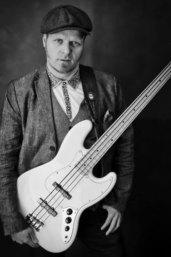 A black and white photo of a man holding a bass guitar.