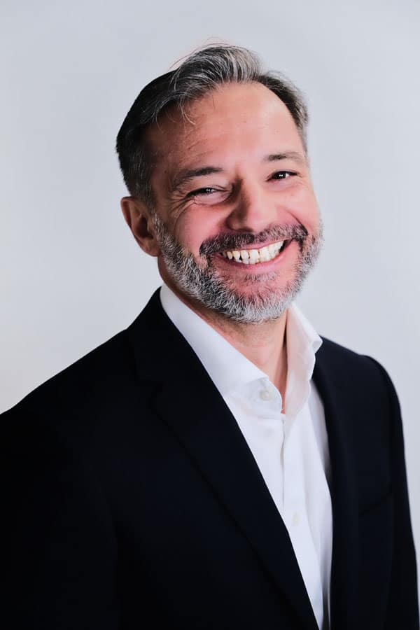 A man in a suit smiling for the camera.