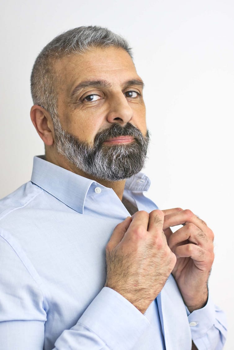 A man with a beard adjusting his shirt.