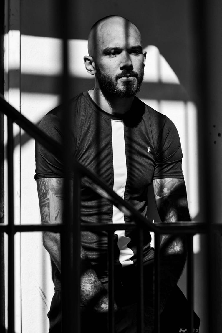 A black and white photo of a man sitting on a railing.