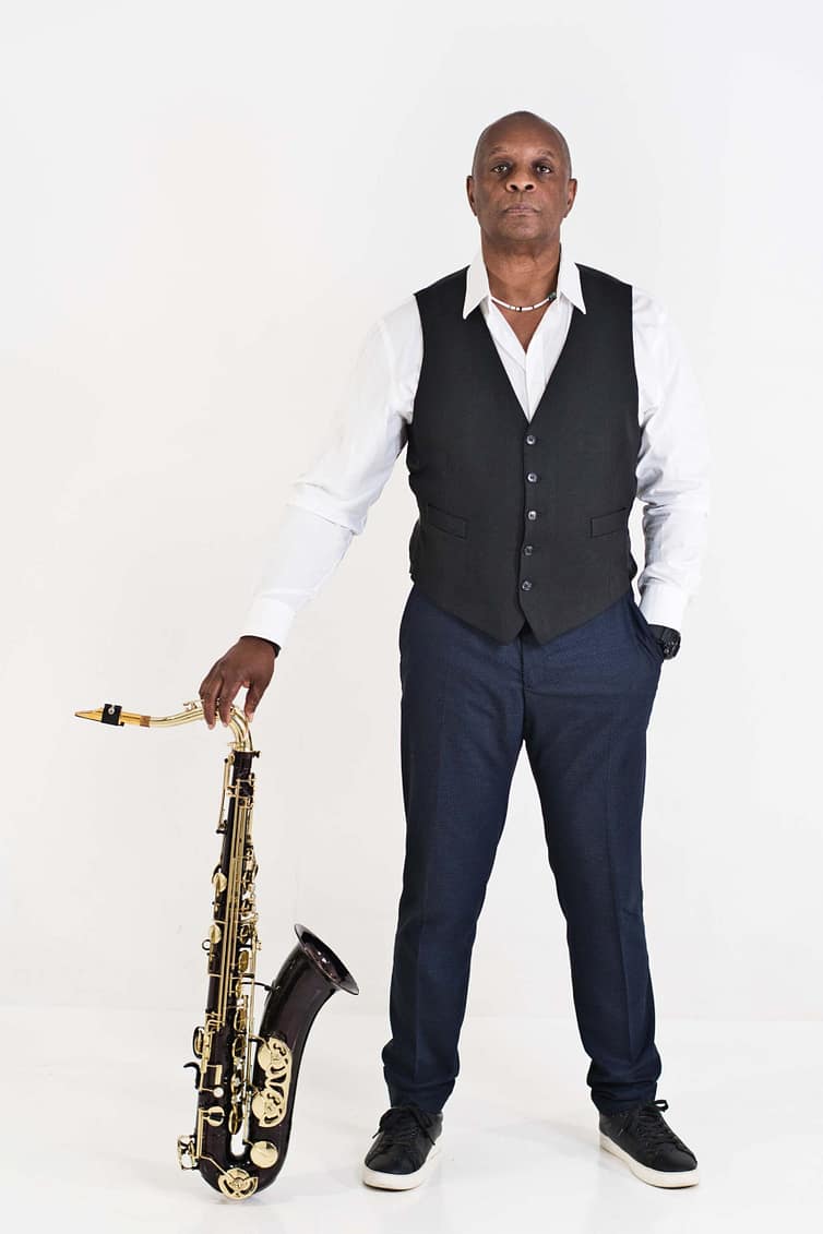 A man holding a saxophone in front of a white background.