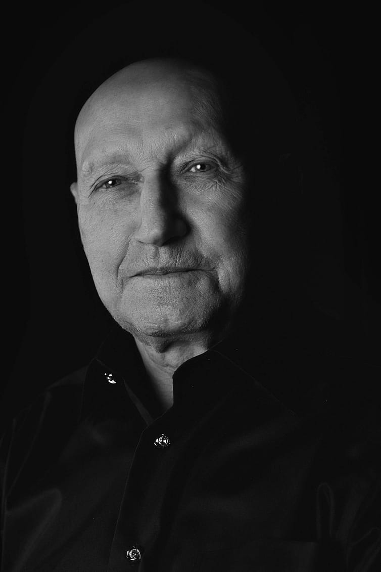 A black and white photo of a man in a black shirt.