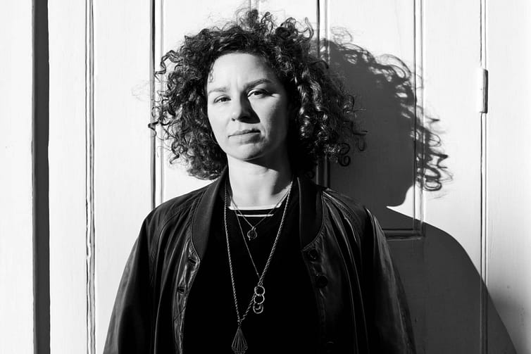 A black and white photo of a woman with curly hair.